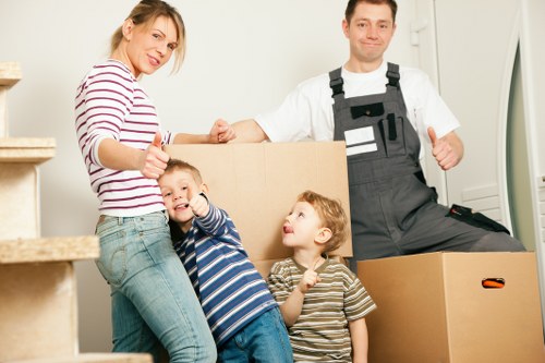 Movers carrying household items through a Mile End flat building